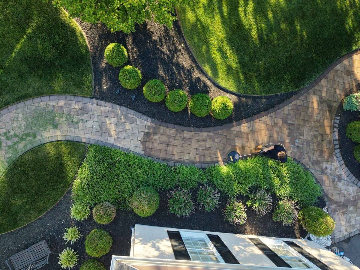 Aerial view of a finished paver walkway and patio winding through landscaped grounds in Bucks County, PA